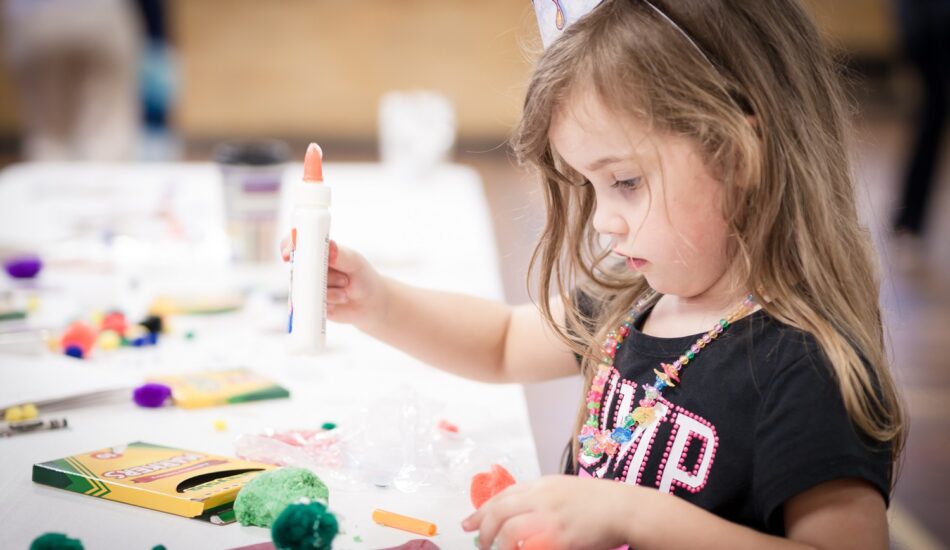 little girl making handcraft at a table at a kids party
